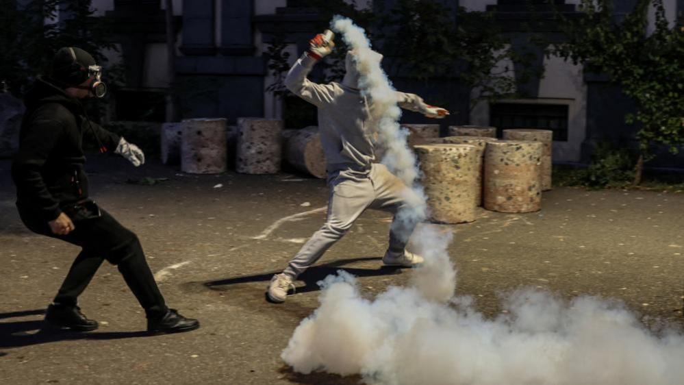 Protesters in Tirana, Albania, throwing tear gas canisters at police