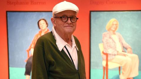 David Hockney in front of his painting
