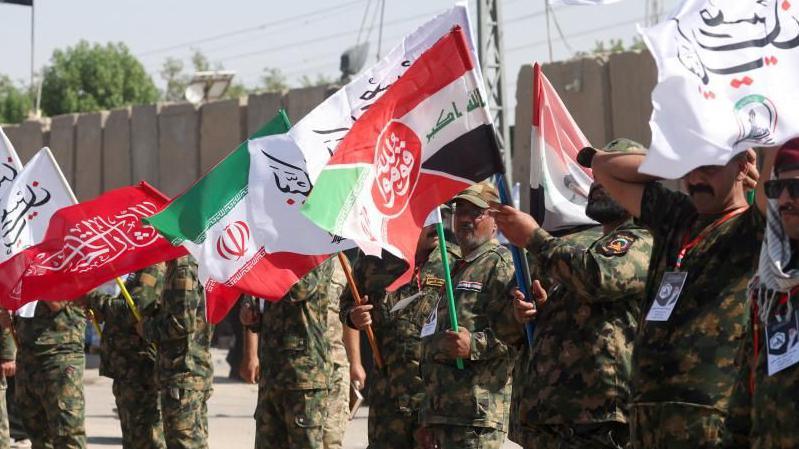 Iranian military personnel standing in line waving flags