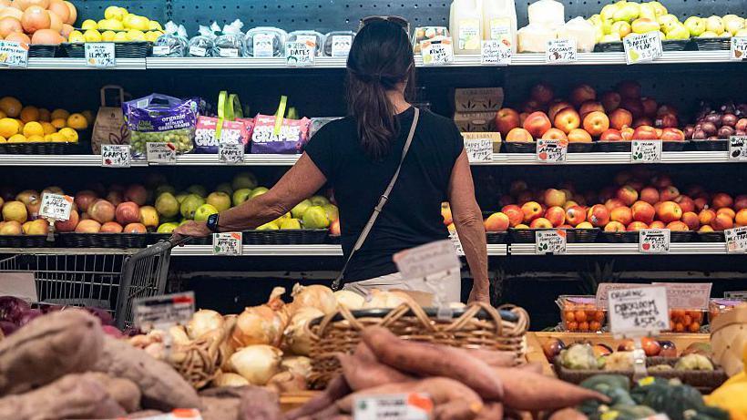 Woman looking at apples in supermarket aisle