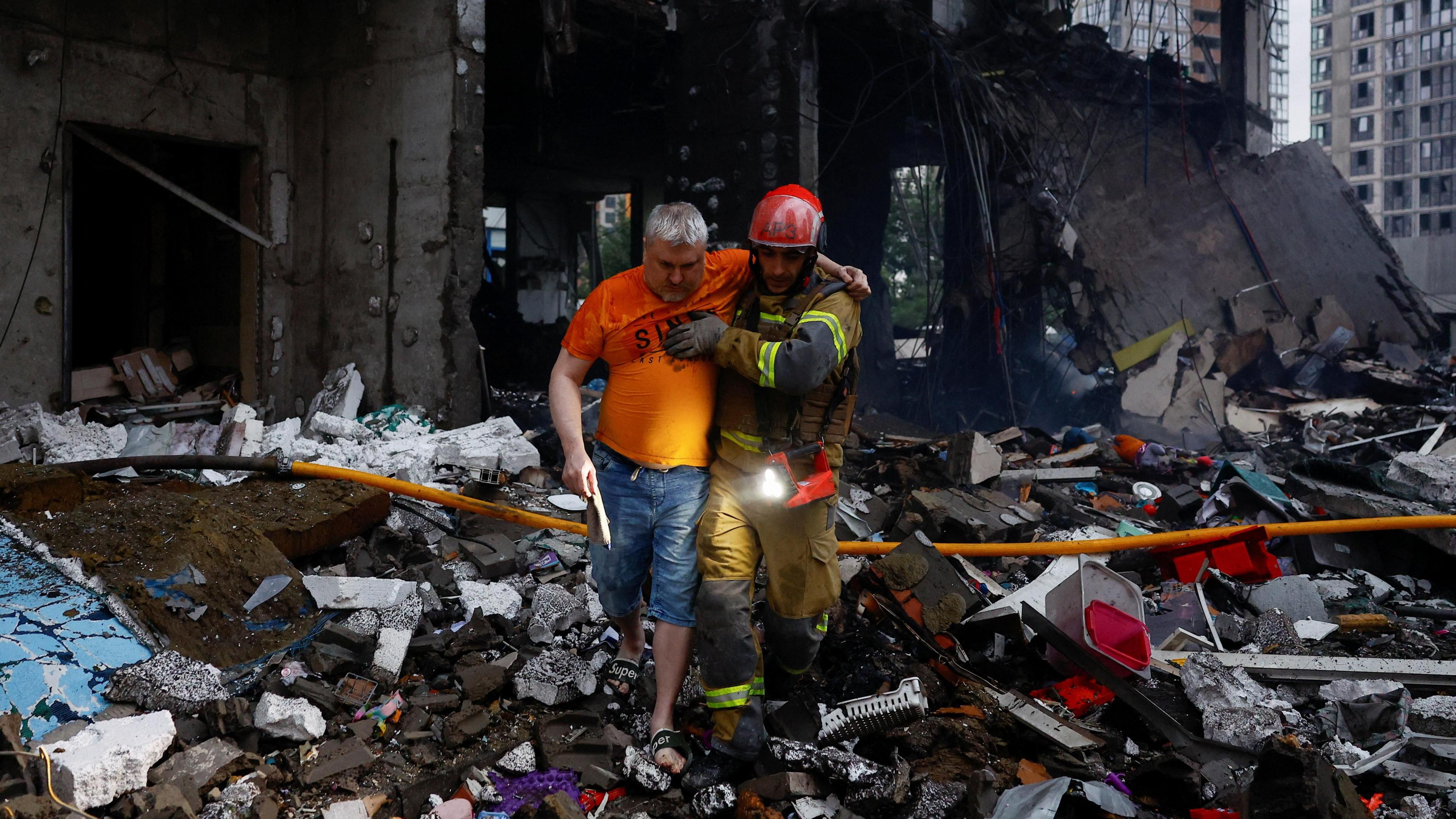 rescuers helping a man amid rubble of an apartment building under Russian missile strikes in Kyiv